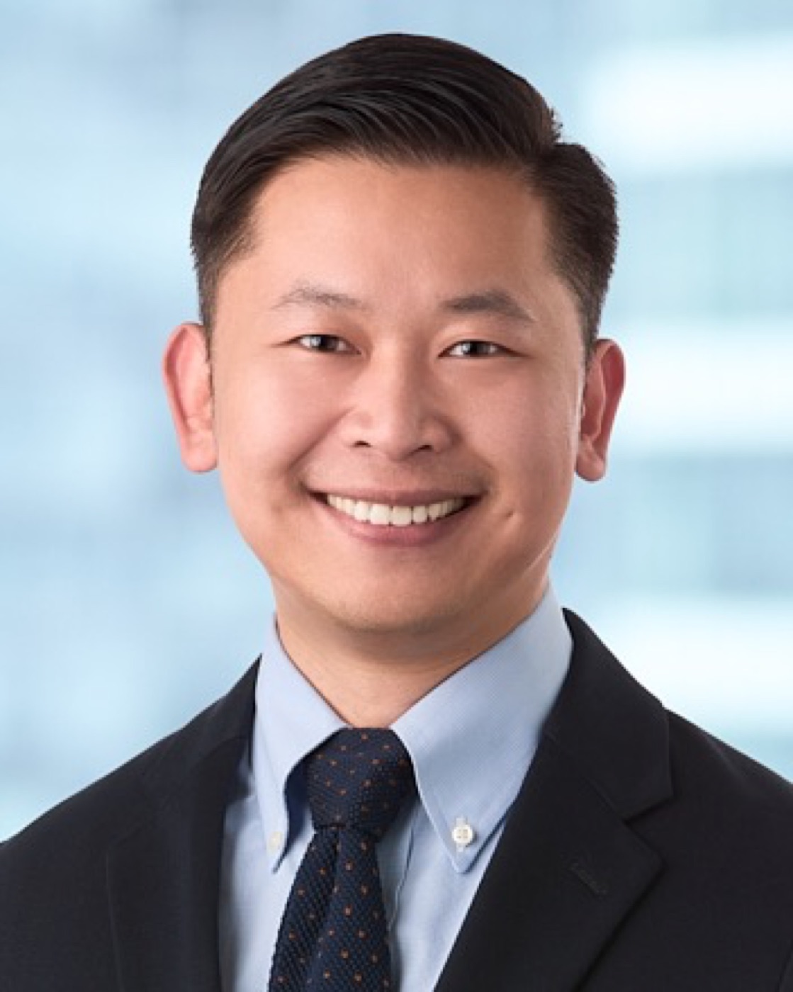 Corporate headshot of a man in a suit, bright background