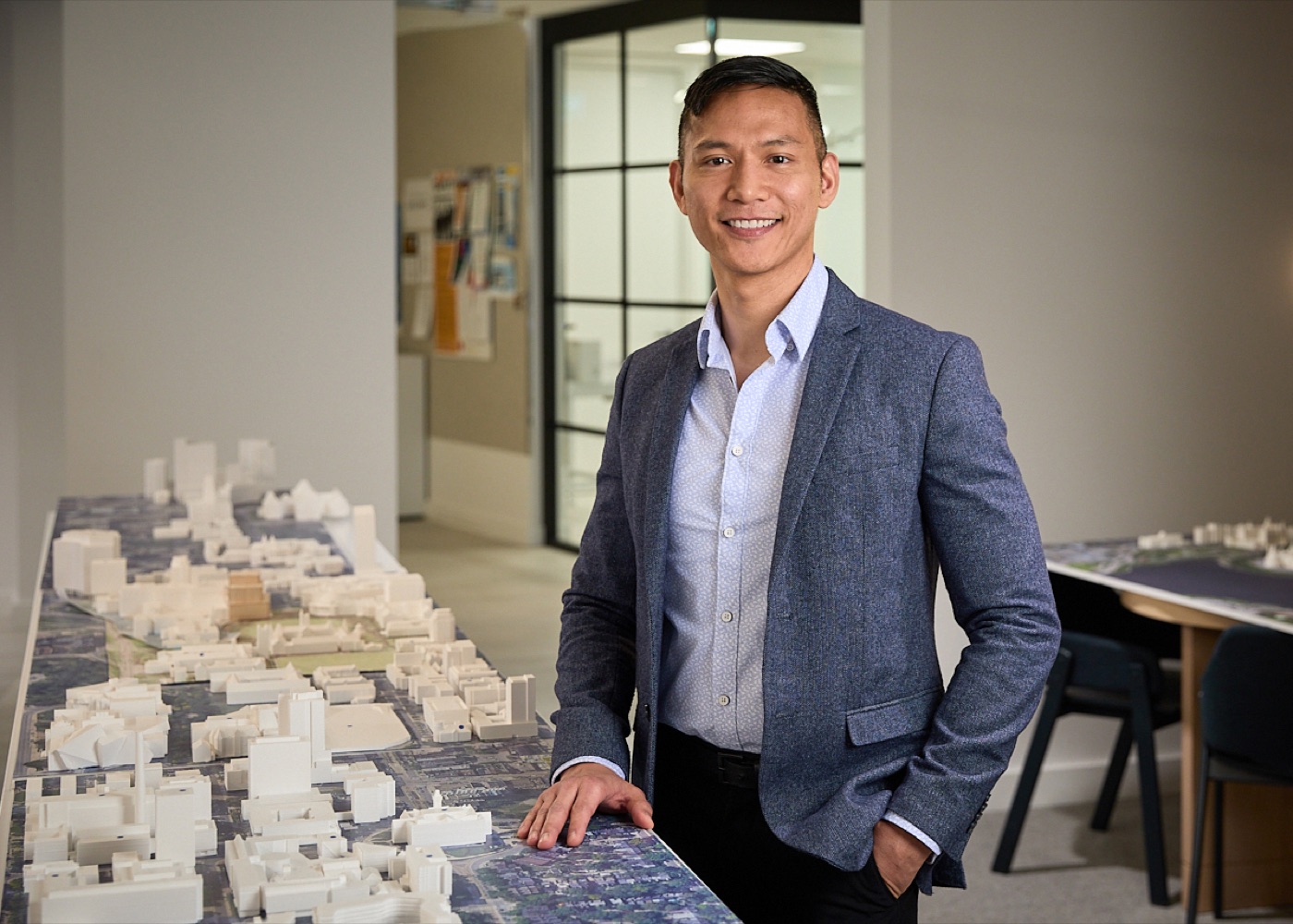 Environmental portrait of a man in a blue-grey blazer, relaxed smile