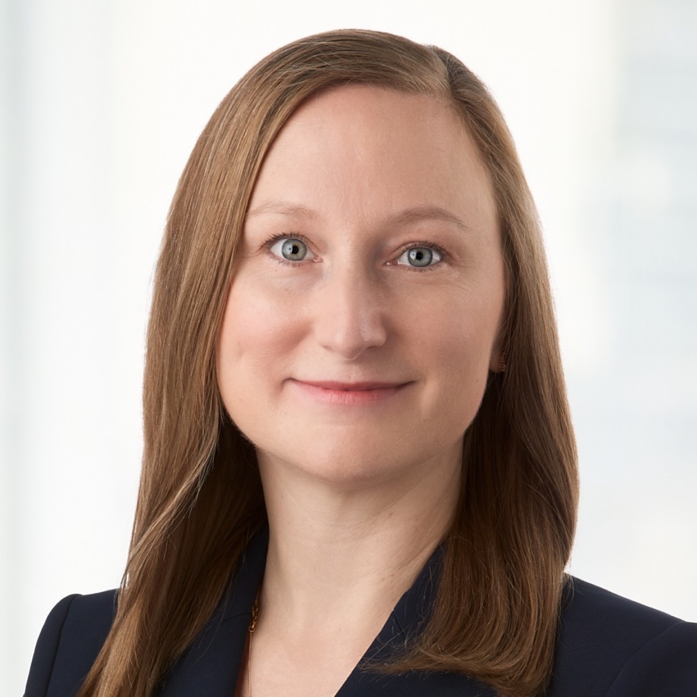 Corporate headshot of a woman in a navy blazer, bright background