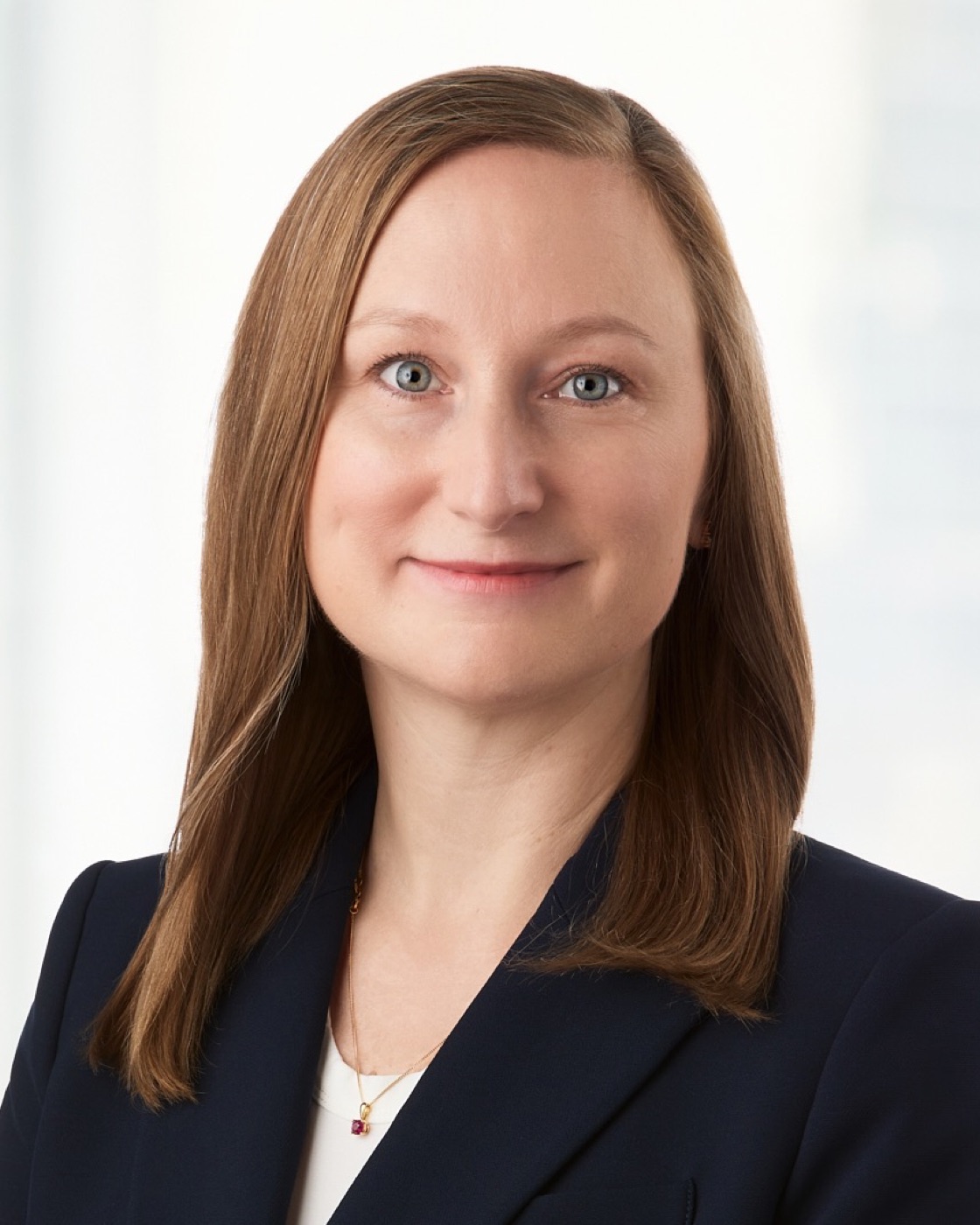 Corporate headshot of a woman in a navy blazer, bright background