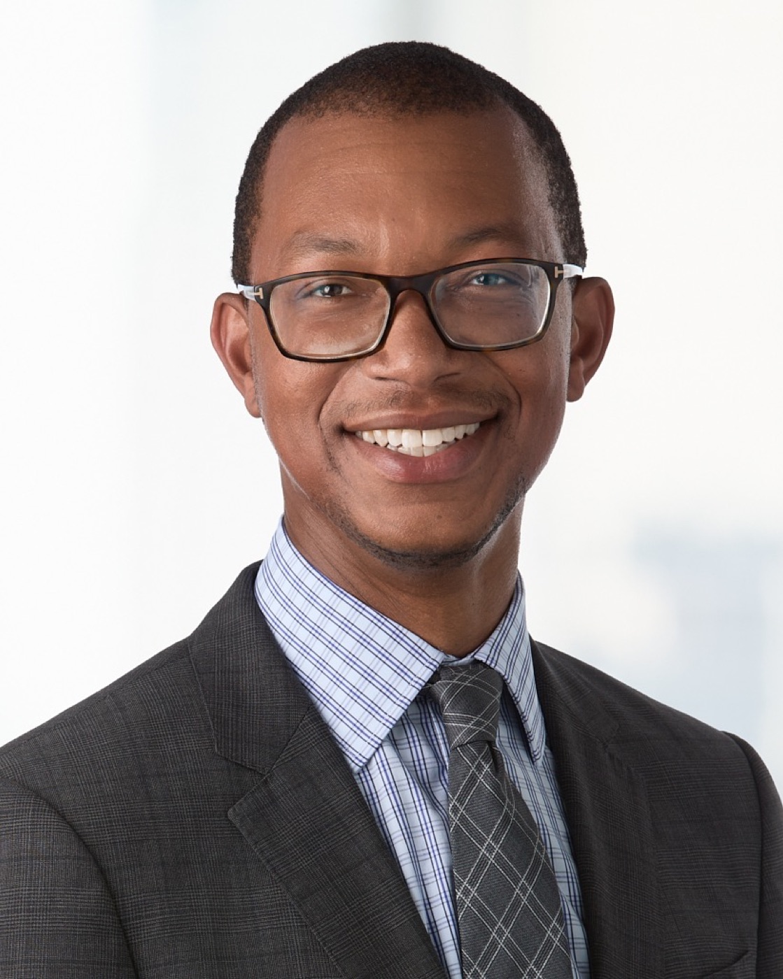 Executive portrait of a man in a dark suit and glasses, studio lighting