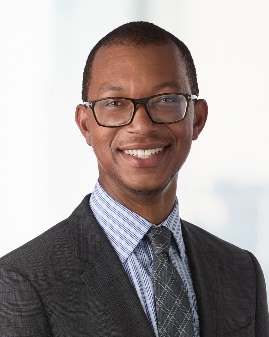 Executive portrait of a man in a dark suit and glasses, studio lighting