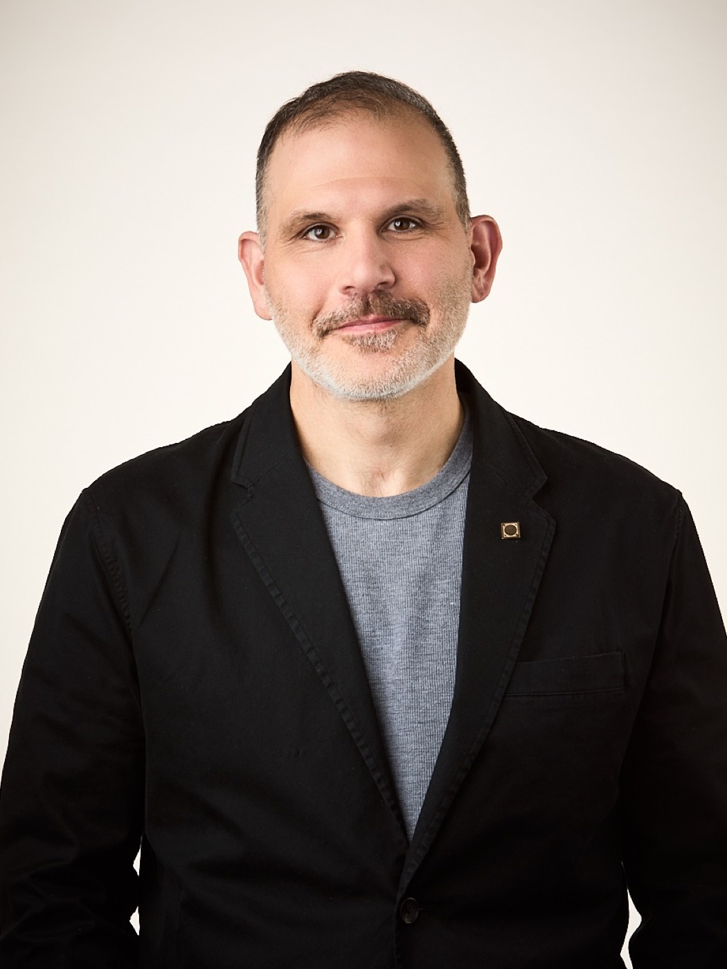 Corporate headshot of a man in a jacket, warm studio light