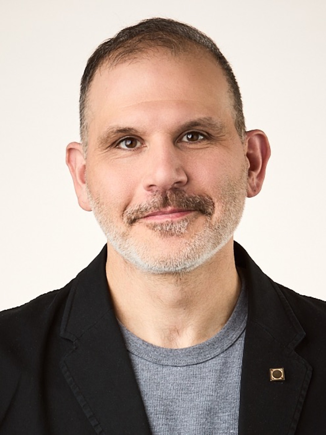 Corporate headshot of a man in a jacket, warm studio light